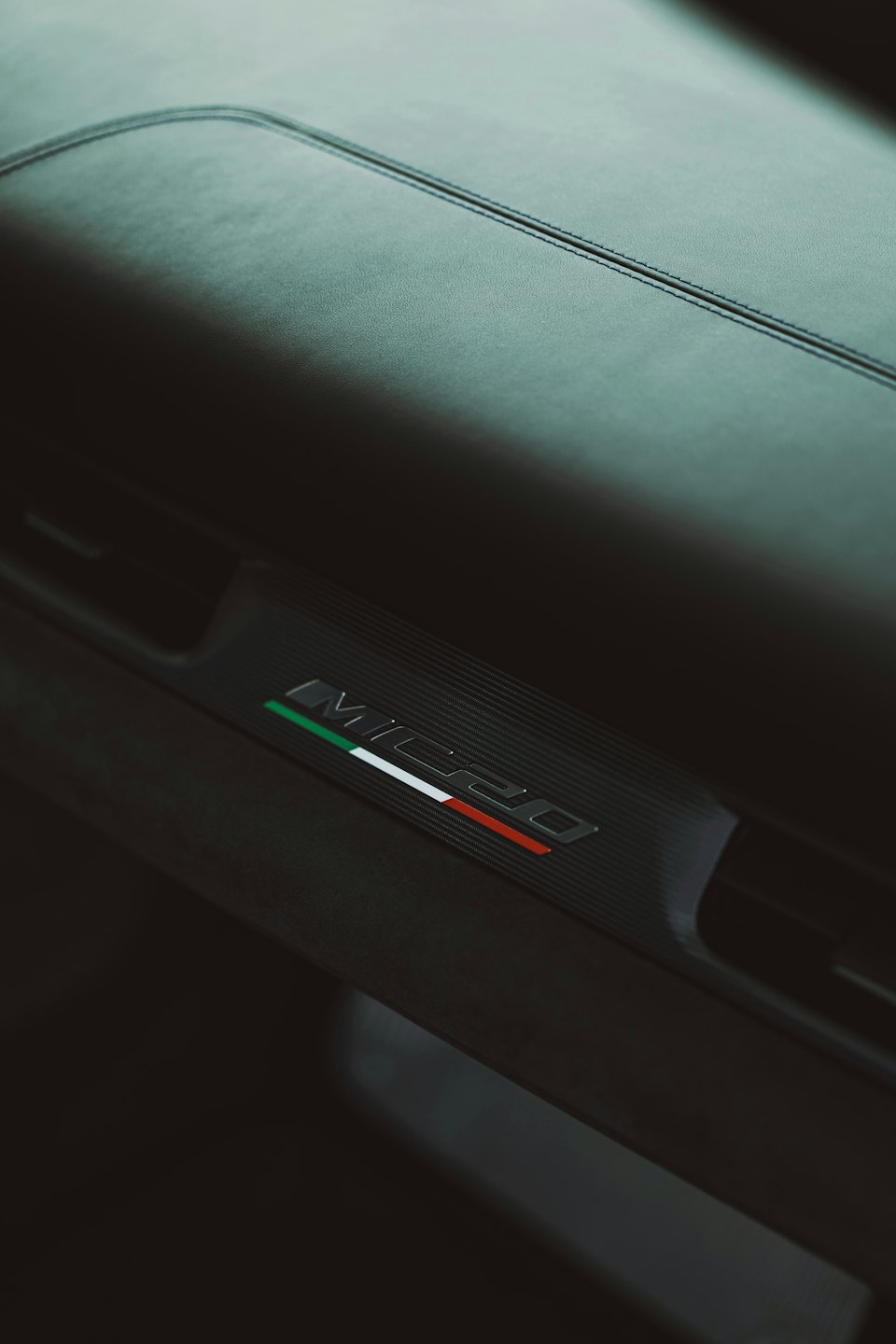 Emblema MC20 con i colori della bandiera italiana su un interno auto.
