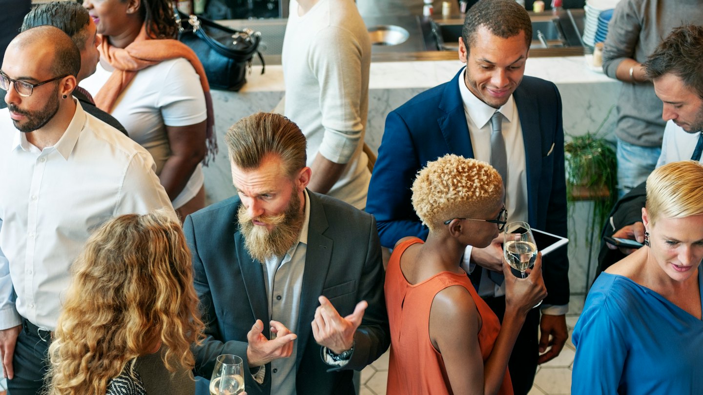 Professionisti che socializzano e tengono bicchieri di vino a un evento.
